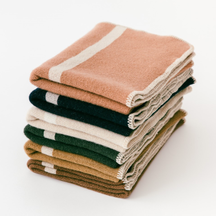 A stack of folded woollen blankets from Foxtrot Home in a range of colours.