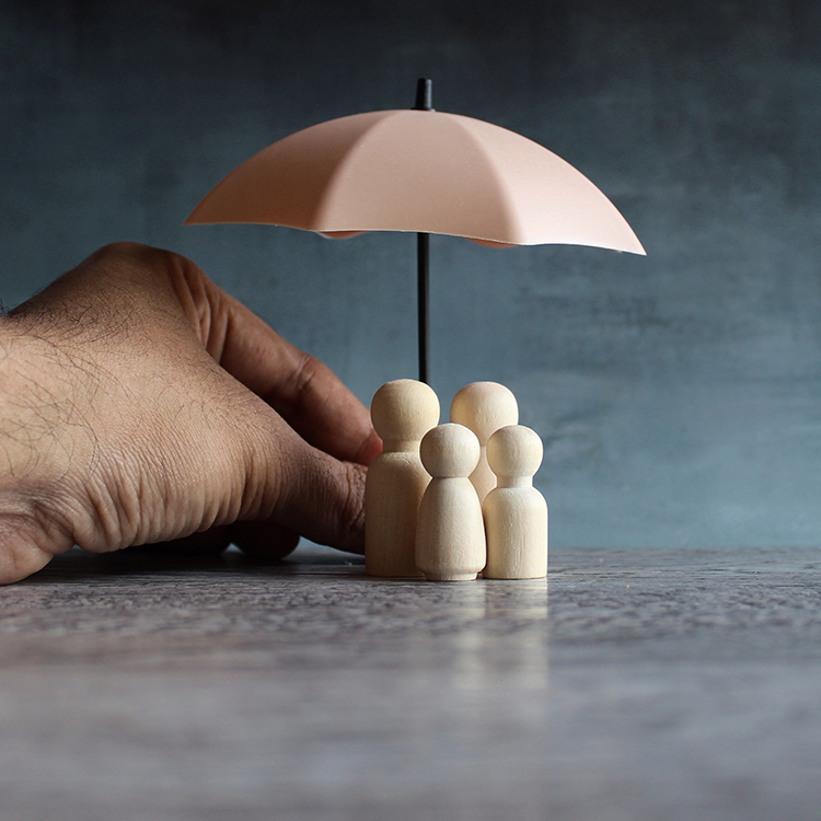 4 wooden pegs representing family unit that are covered by a model umbrella.