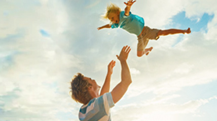 A man playfully throwing his son in the air