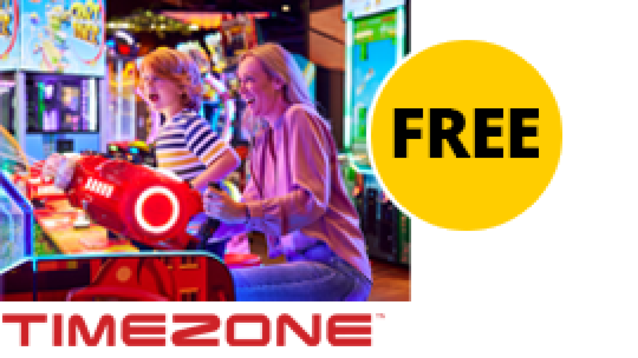 A sticker with the text Free overlaying a photo of  a woman and her young child playing on an arcade machine