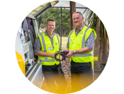 Two AA roadservice staff smiling at the camera holding a cord