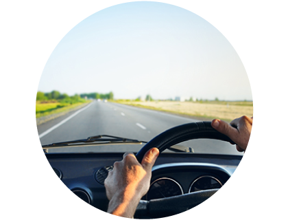 Man driving on an open road shown from behind the steering wheel