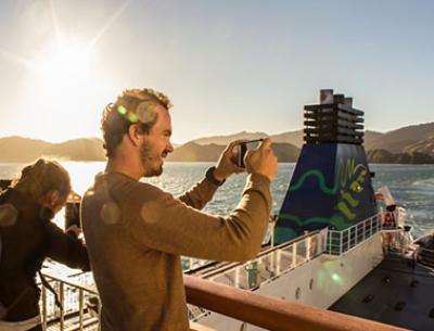 Man taking a photo with his phone from the deck of the ferry