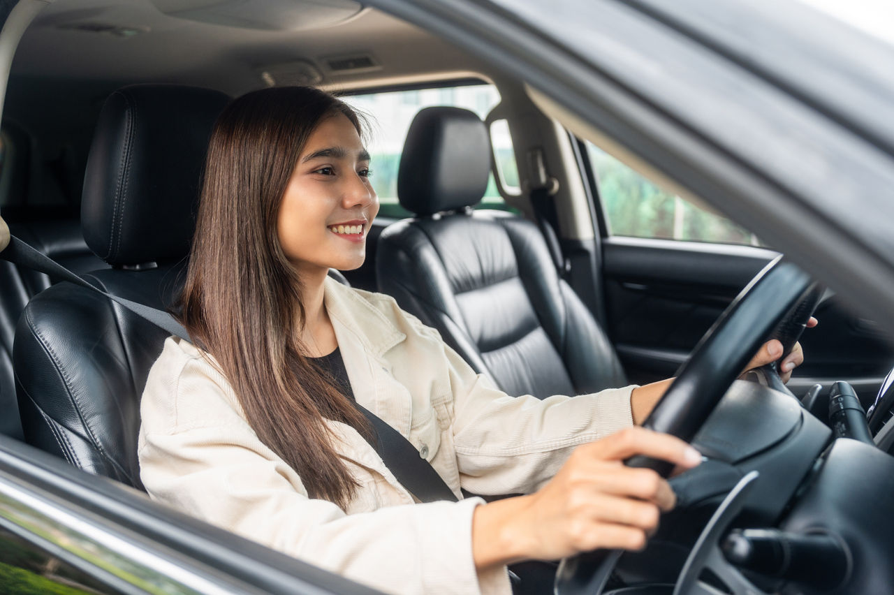 Happy smiling young woman driving vehicle on the road