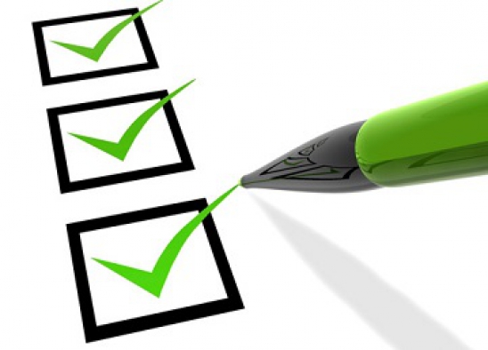 A close up view of a green pen marking check marks on a checklist