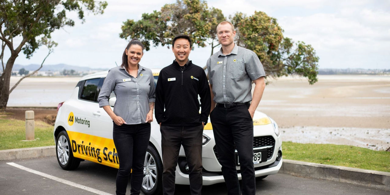 Three AA Driving School instructors in front of AA Driving School branded car