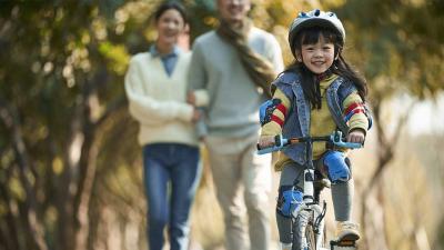 Young girl on her bike with her parents in the foreground