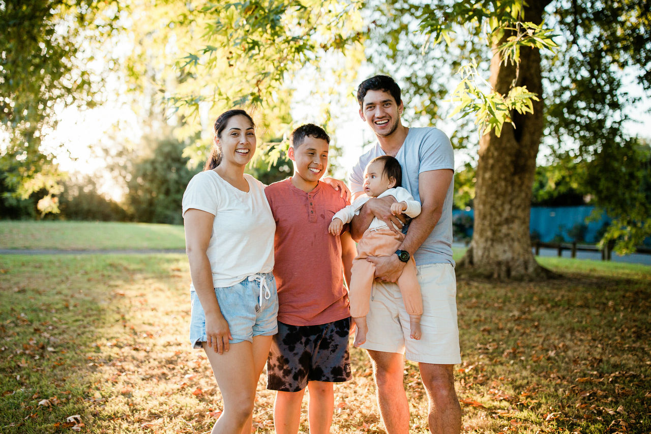 Young family in park under tree smiling