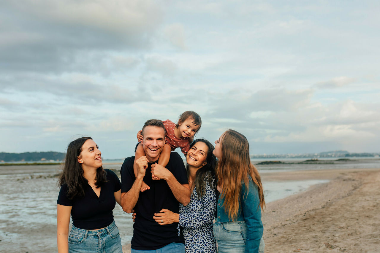 Family laughing together on the shore of a beach