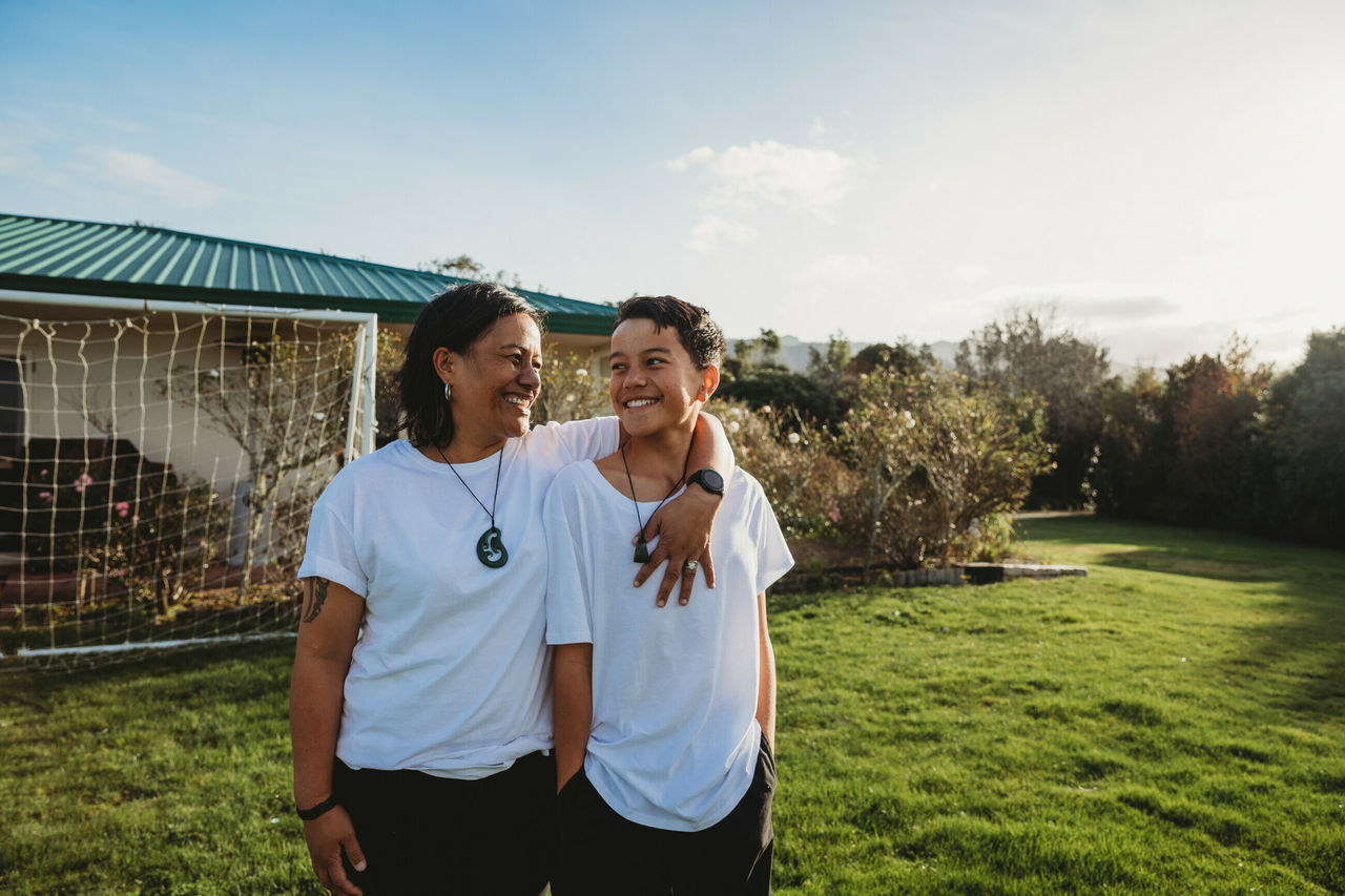 Mum and son standing in backyard smiling