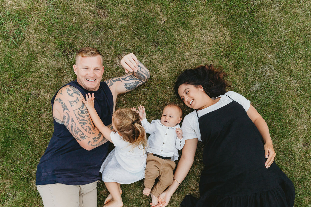 Family with baby and toddler lying on grass 