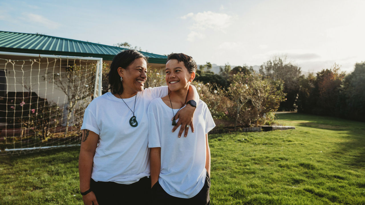Mum and son standing in backyard smiling
