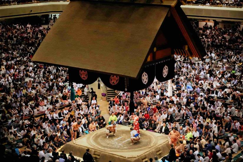 Sumo wrestlers on stage in a crowded stadium