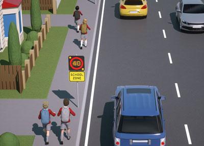Simulated road of a school zone showing children walking on a pavement alongside cars on the road going 40 km/h speed