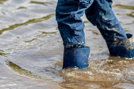 Muddy gumboots walking through flood water