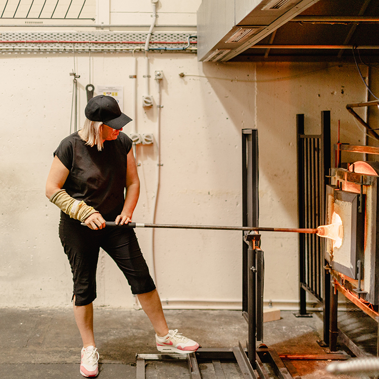 Katie collects molten glass to turn into art. Photo by Alanah Brown.