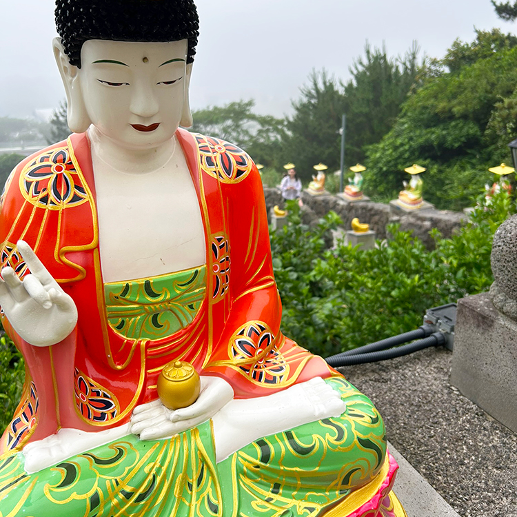 A path leading to a Buddhist shrine on Jeju Island is lined with colourful Buddha statues.