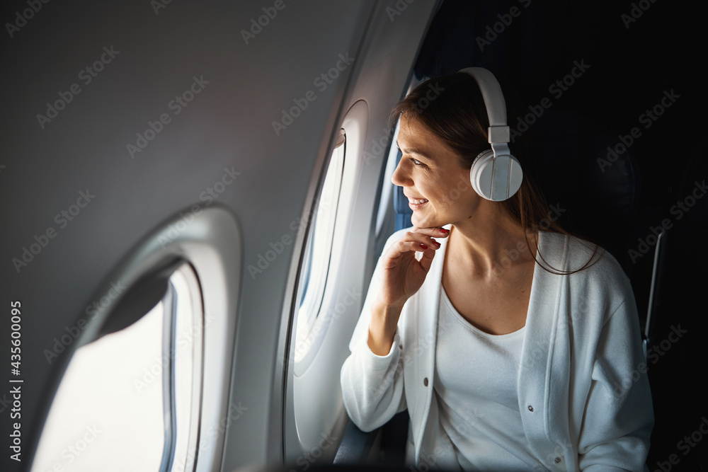 Woman in window seat of airplane smiling