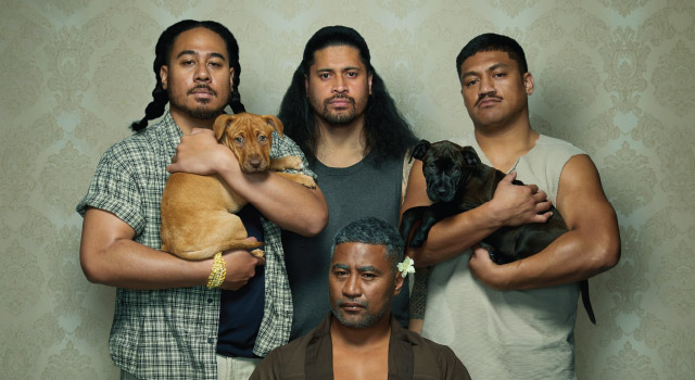 Promotional image of cast, three sons standing holding two dogs and father in centre