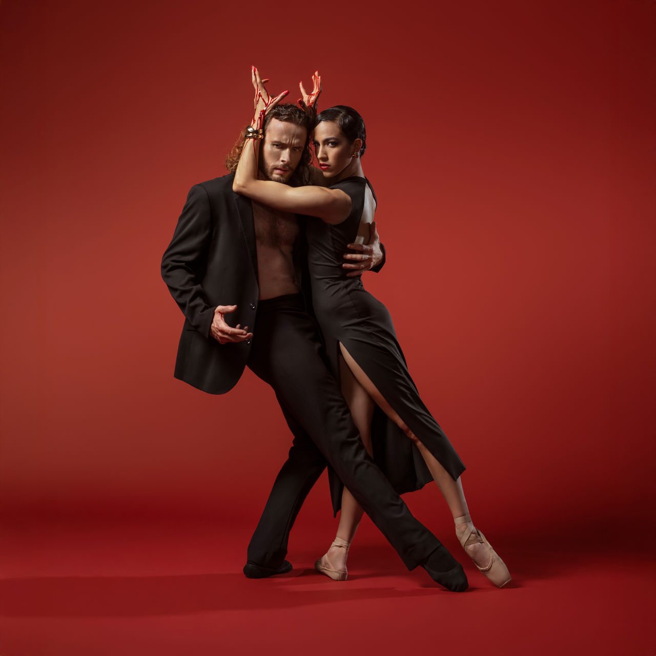 Macbeth promotional image of man and woman dancing intimately with a red back drop 