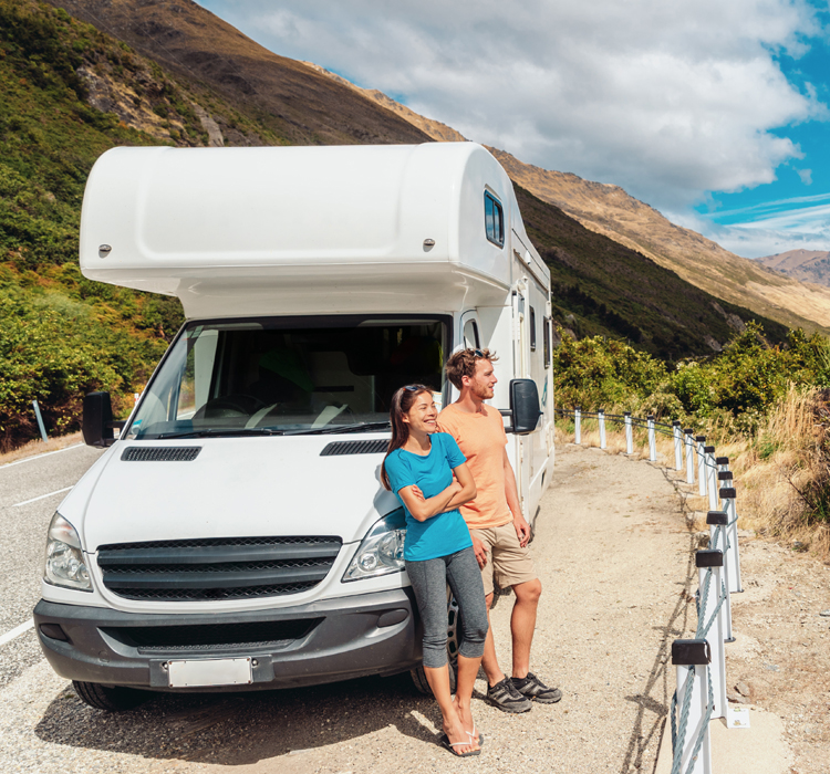 young couple leaning against a motorhome to take in a roadside view