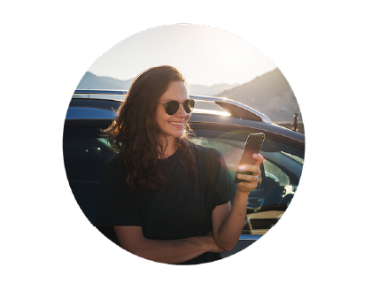Woman smiling while wearing sunglasses and looking at her phone
