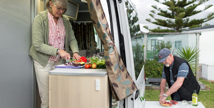 An older couple preparing food in a Maui campervan kitchen set up.